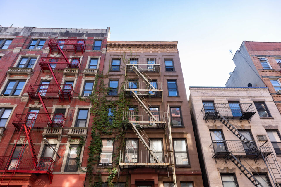 Looking up at beautiful colorful old residential buildings with fire escapes in SoHo of New York City.