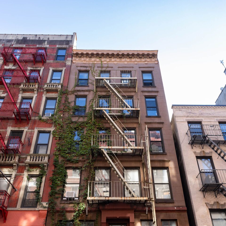 Looking up at beautiful colorful old residential buildings with fire escapes in SoHo of New York City.