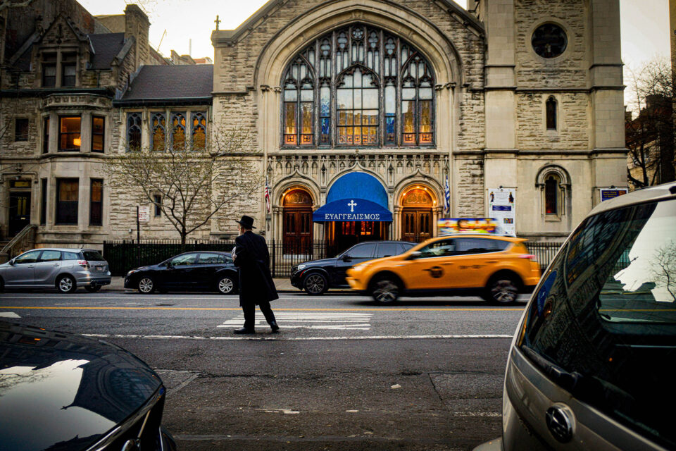 Rabbi walking across the street in front of the Greek Orthodox Church, New York City, United States