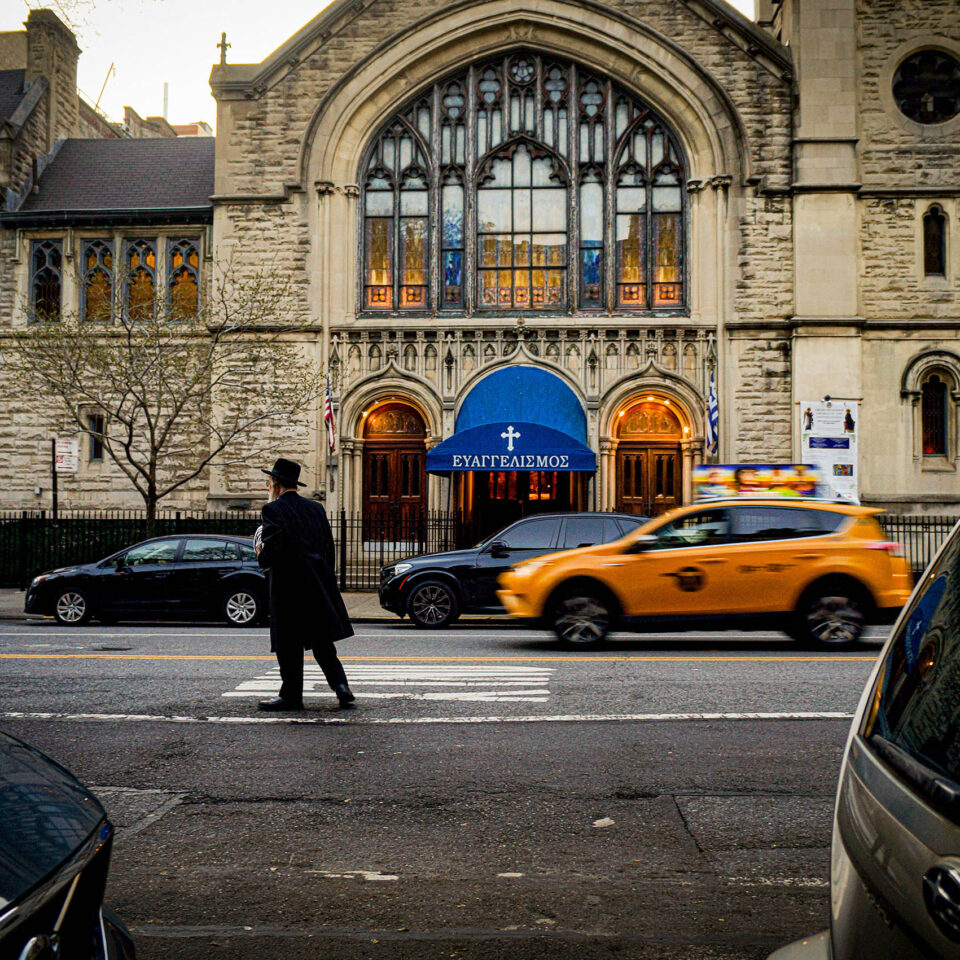 Rabbi walking across the street in front of the Greek Orthodox Church, New York City, United States