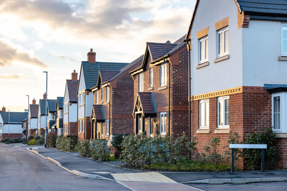 Houses in England with typical red bricks at sunset - Main street in a new estate with typical British houses on the side
