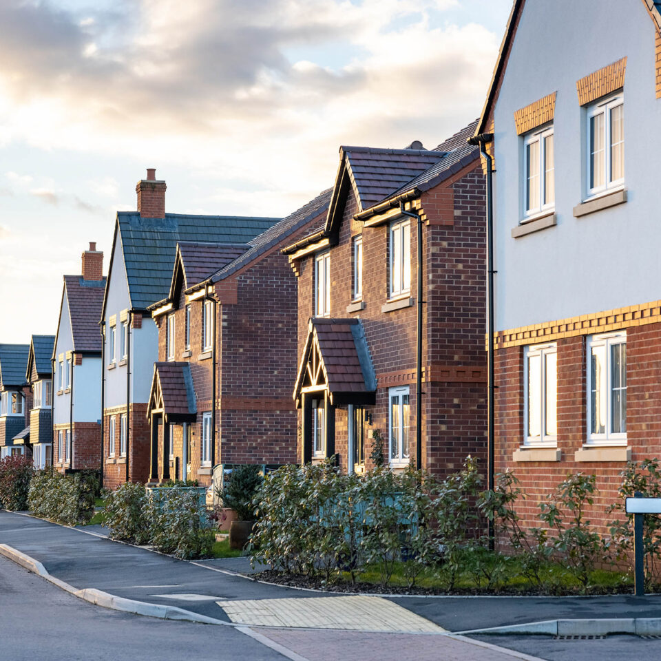 Houses in England with typical red bricks at sunset - Main street in a new estate with typical British houses on the side